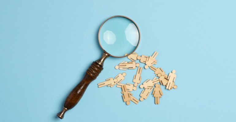 wooden-men-and-a-magnifying-glass-on-a-blue-backgr-2023-11-27-04-54-49-utc